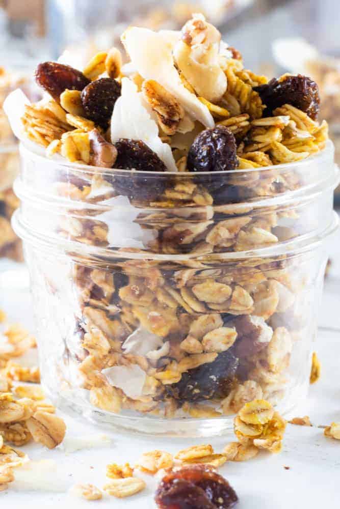 Crunchy homemade granola in mason jar on white table.