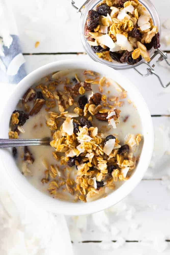 Cereal in milk in white bowl and all-natural granola in small jar.