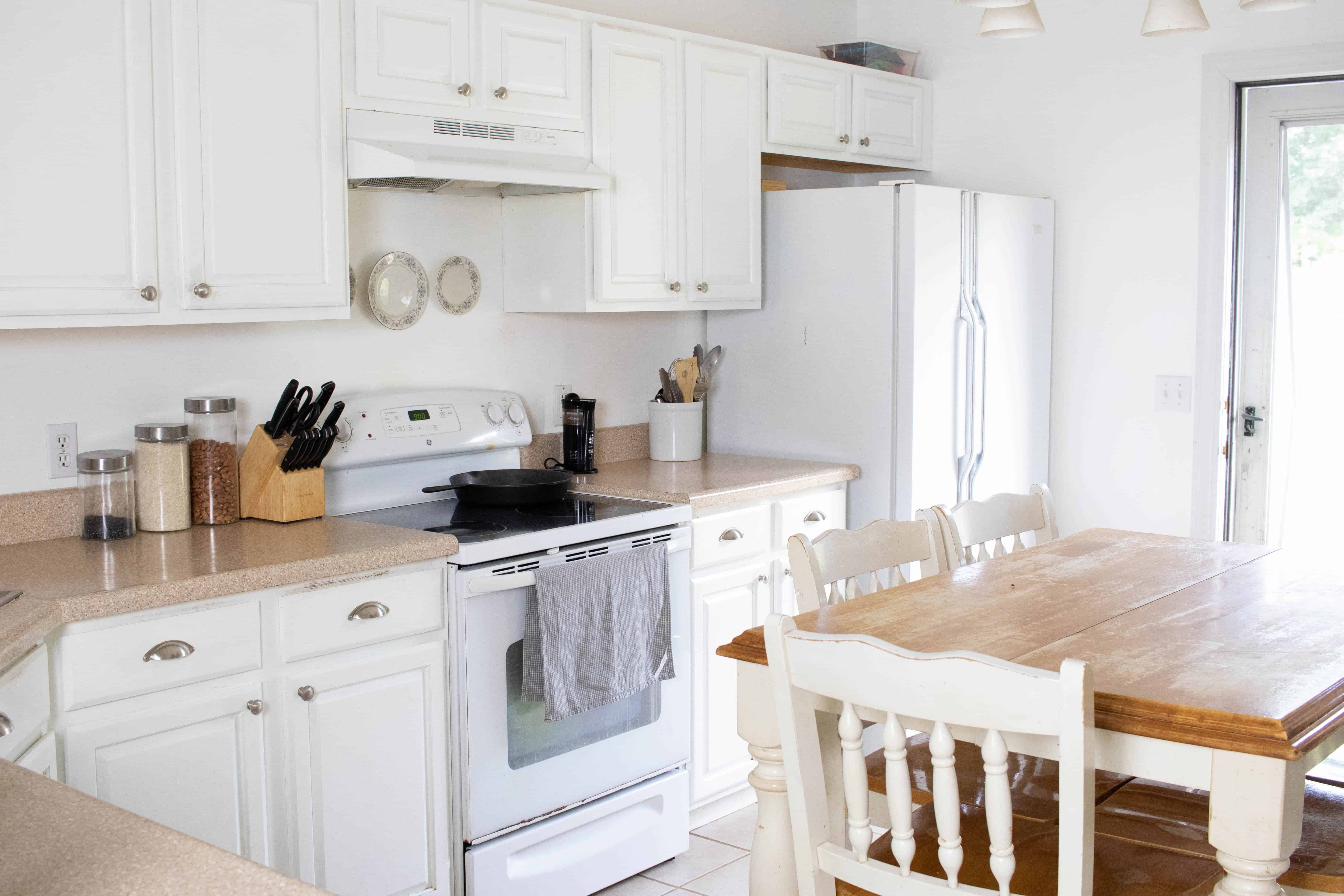 Clean organized kitchen with white cabinets, brown countertops, and white appliances.