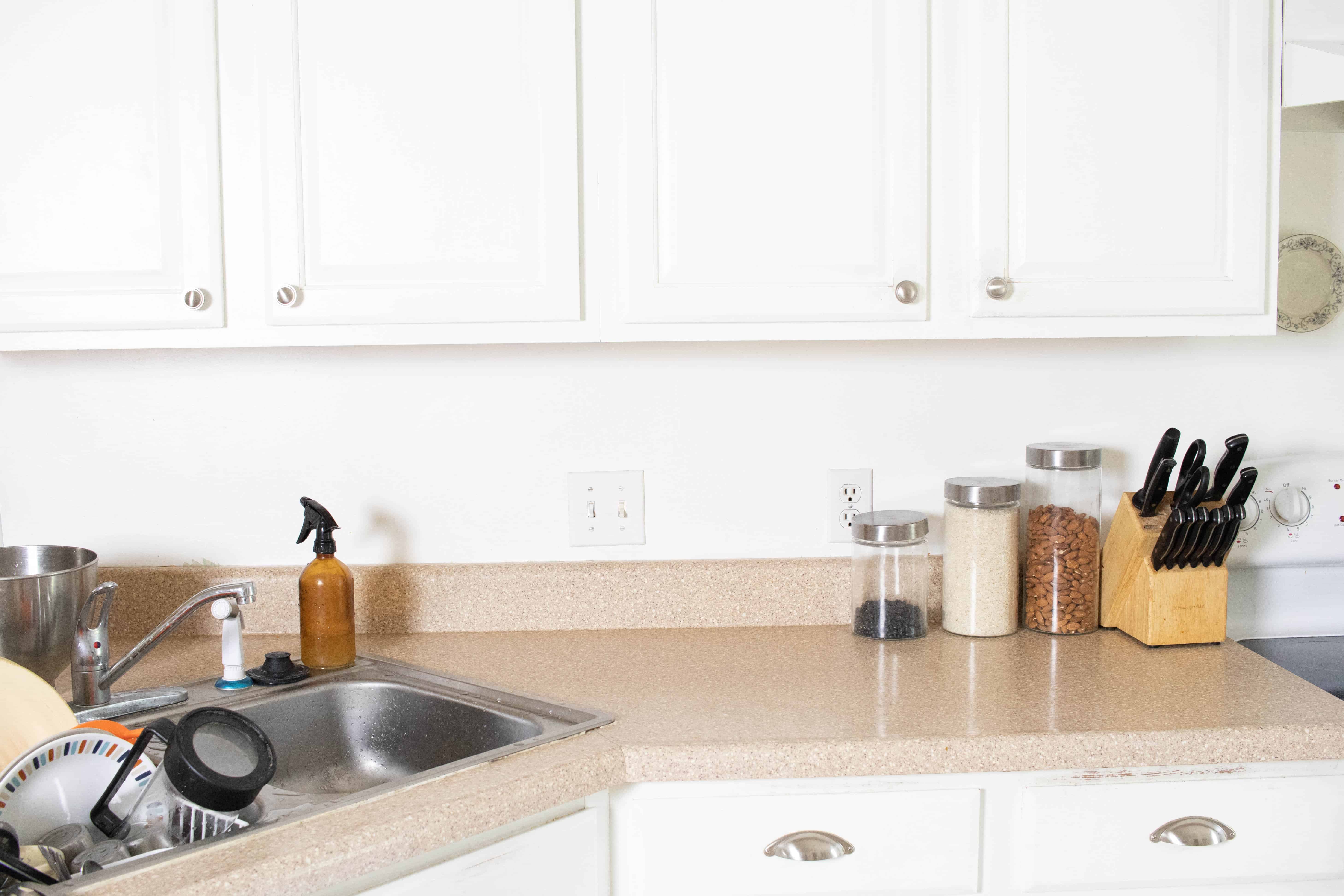 A kitchen with white cabinets and brown counter top.