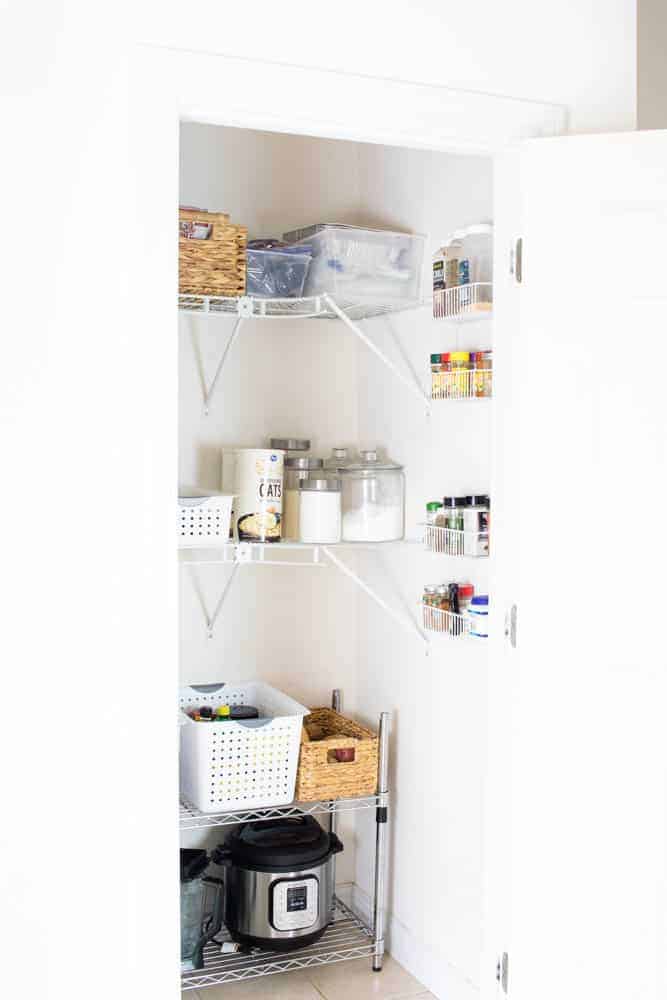Organized pantry with white walls and white shelves. 