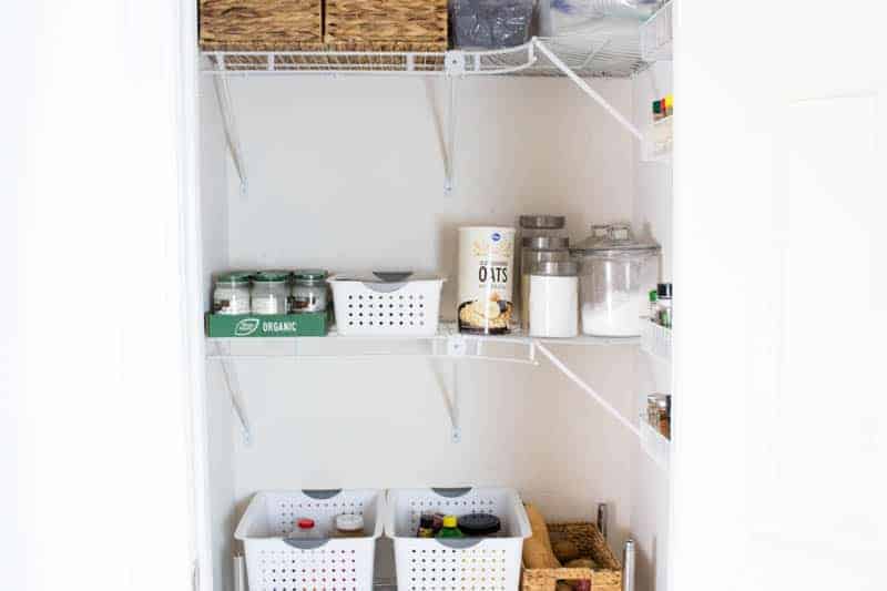 Storage containers in clean white pantry.