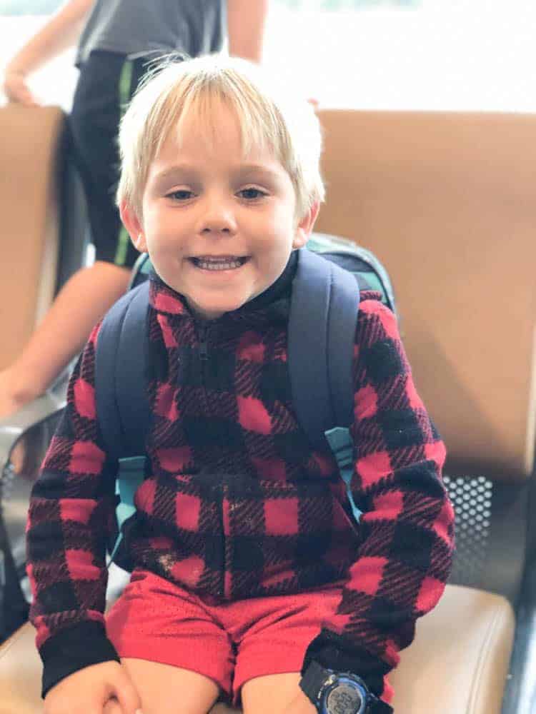 Little boy with backpack sitting in airport ready for his first time flying.