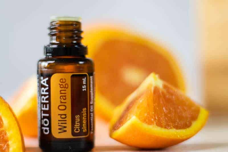 Wild orange essential oil and fresh orange slices on table.