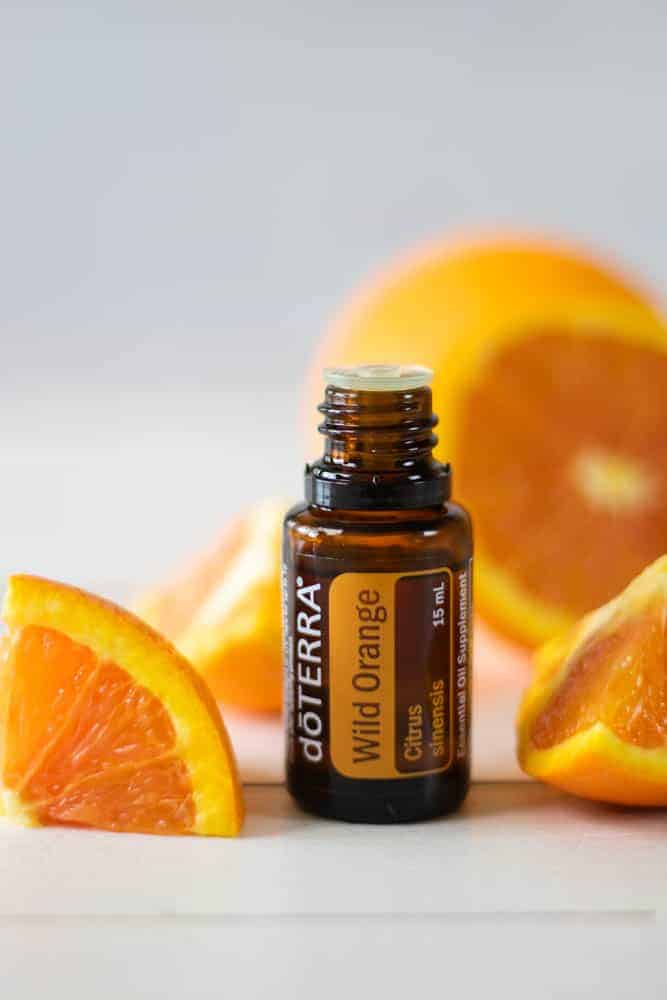 DoTERRA essential oil and orange slices on white backdrop.