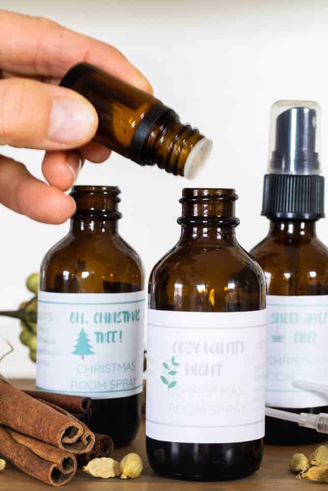 Dropping essential oils into a holiday room spray bottle.