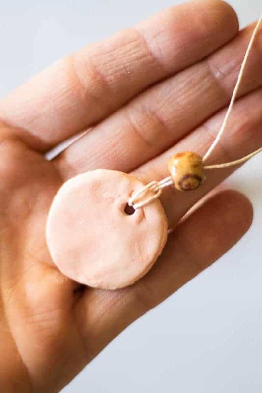 Pure clay diffuser necklace in palm of hand.