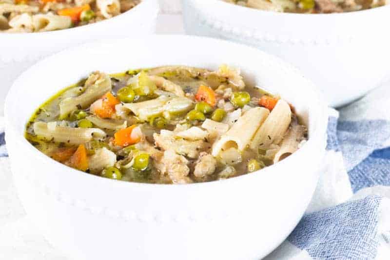 Turkey soup with noodles and vegetables in white bowl.