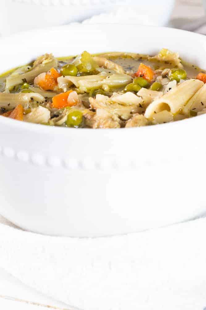 White bowl full of turkey noodle soup.