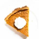 slice of pumpkin pie with whipped cream on white plate
