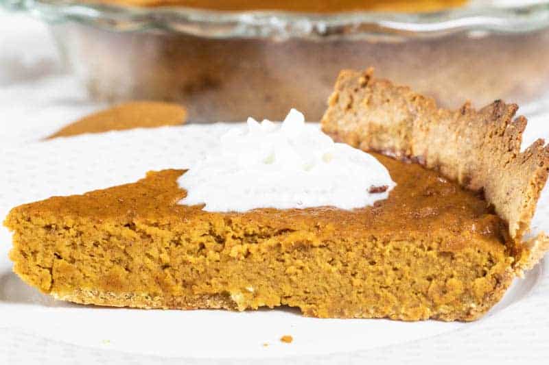 Slice of homemade pumpkin pie on glass white plate.