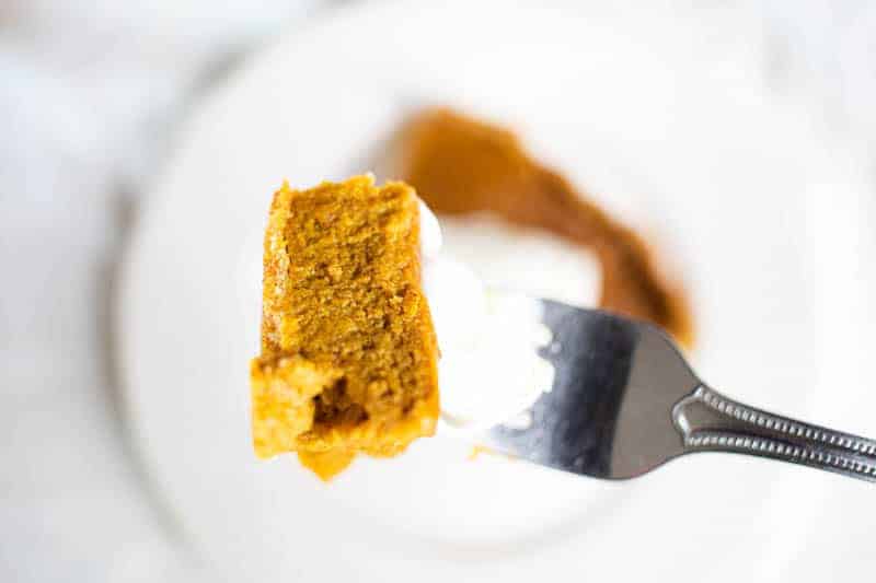 Piece of pumpkin pie with whipped coconut cream on fork.