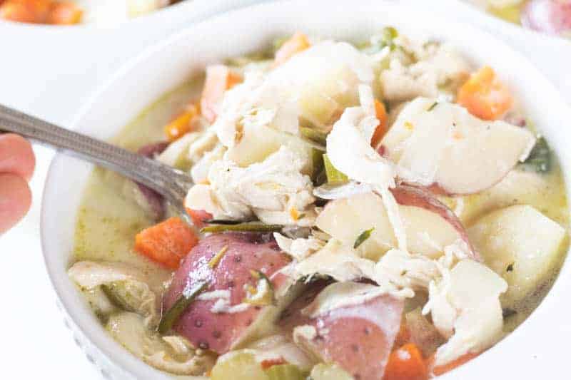 Healthy whole 30 creamy chicken vegetable soup in white bowl with silver spoon.