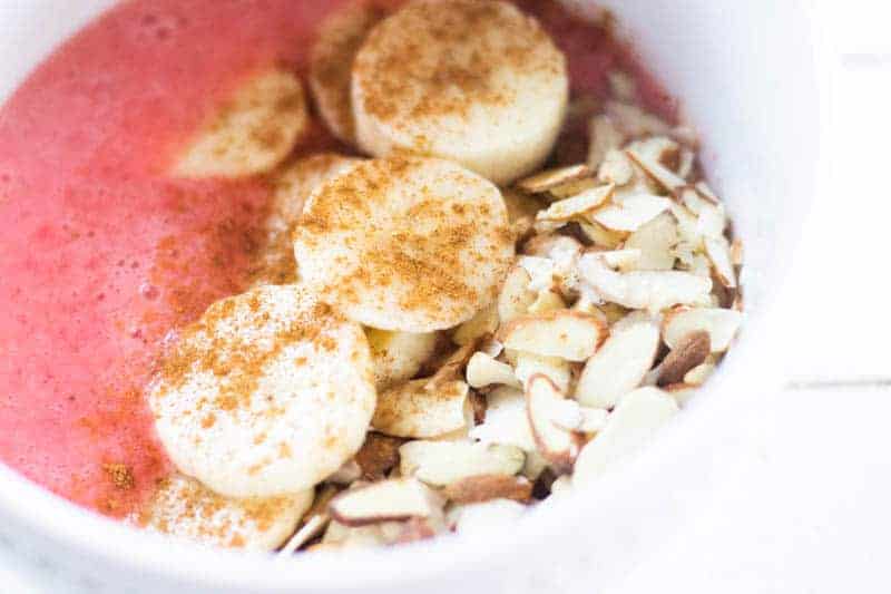 Strawberry crunch smoothie bowl with chopped nuts and bananas.