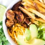 southwest chicken, avocado slices, shredded cheese, and French fries in white bowl