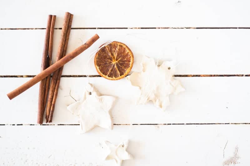 Diffuser ornaments on white ship lap with cinnamon sticks and dried orange slice.