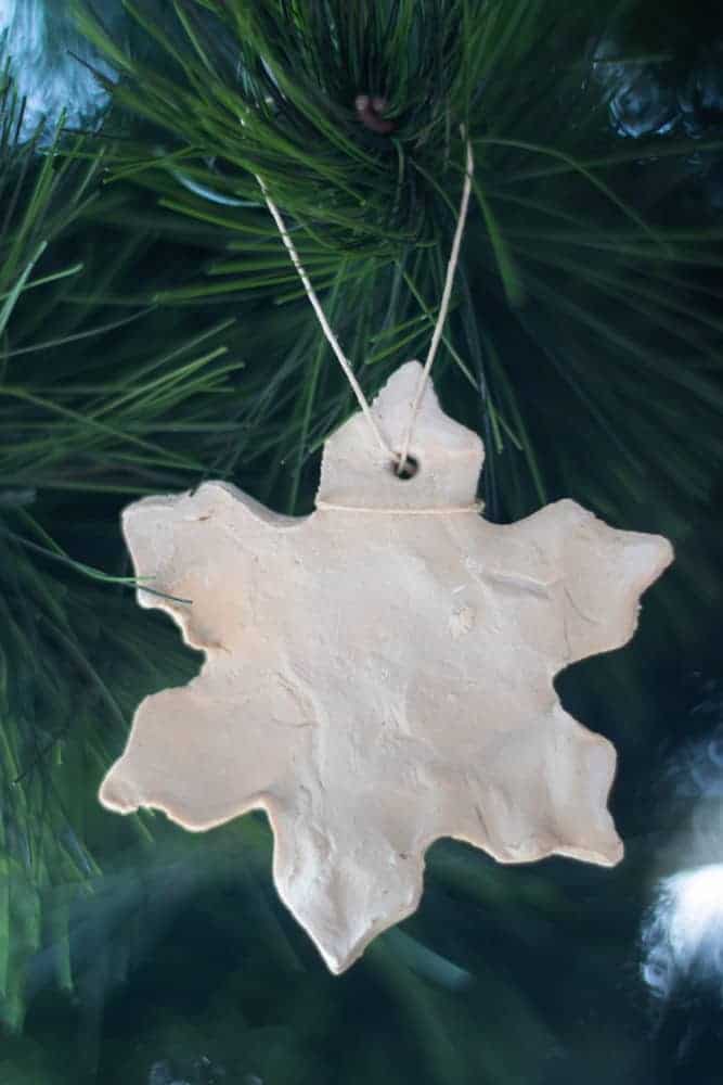 Homemade clay ornament hanging on pine tree.