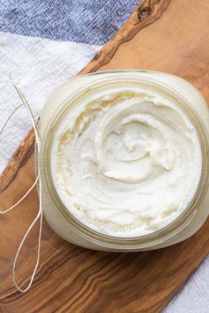 Whipped face lotion in small mason jar on decorative board.