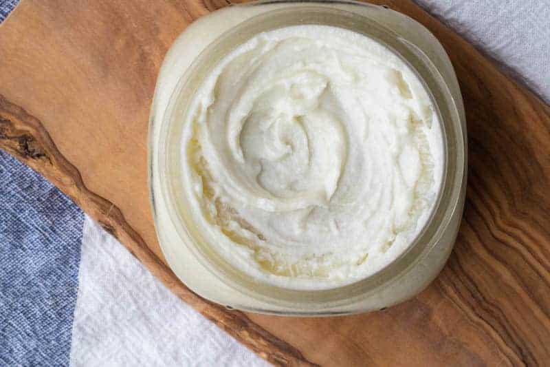 Shea butter lotion in small mason jar on wood.