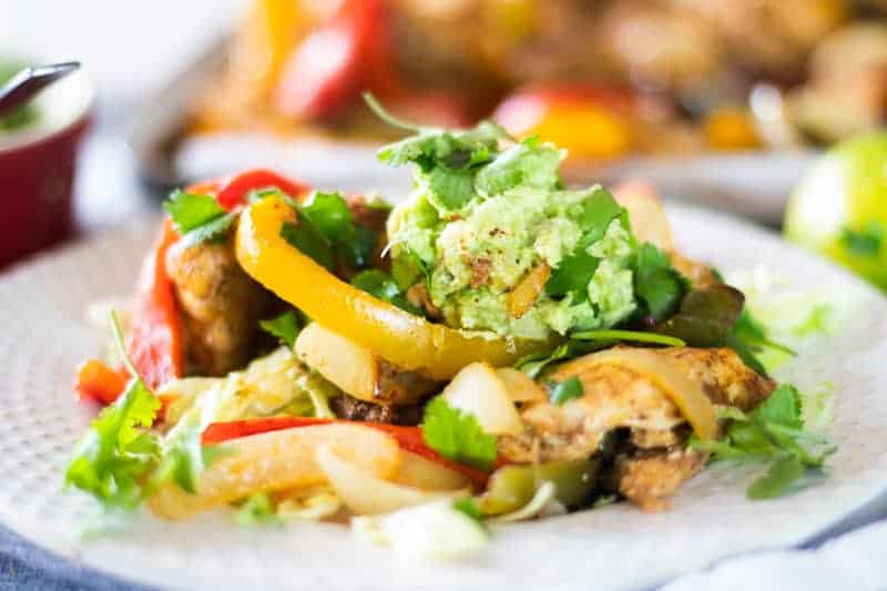 Chicken fajita salad on white plate topped with guacamole and cilantro.