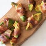 bacon wrapped avocado fries on wood cutting board