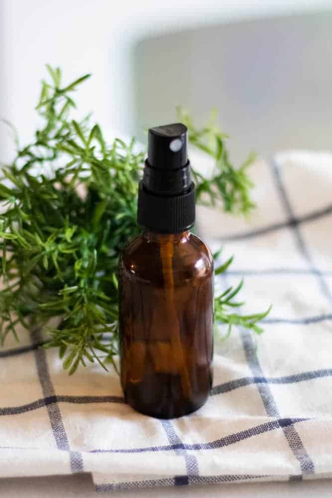 Aftershave in spray bottle on vanity with a white checkered towel and lavender sprigs. 