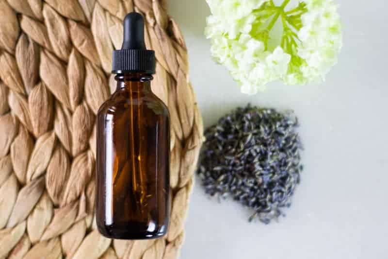anti-aging serum in glass amber colored dropper bottle on a wooden woven mat with white marble background