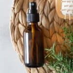 amber spray bottle of hair spray with rosemary and tan brush