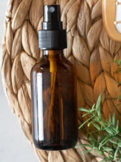 amber spray bottle of hair spray with rosemary and tan brush