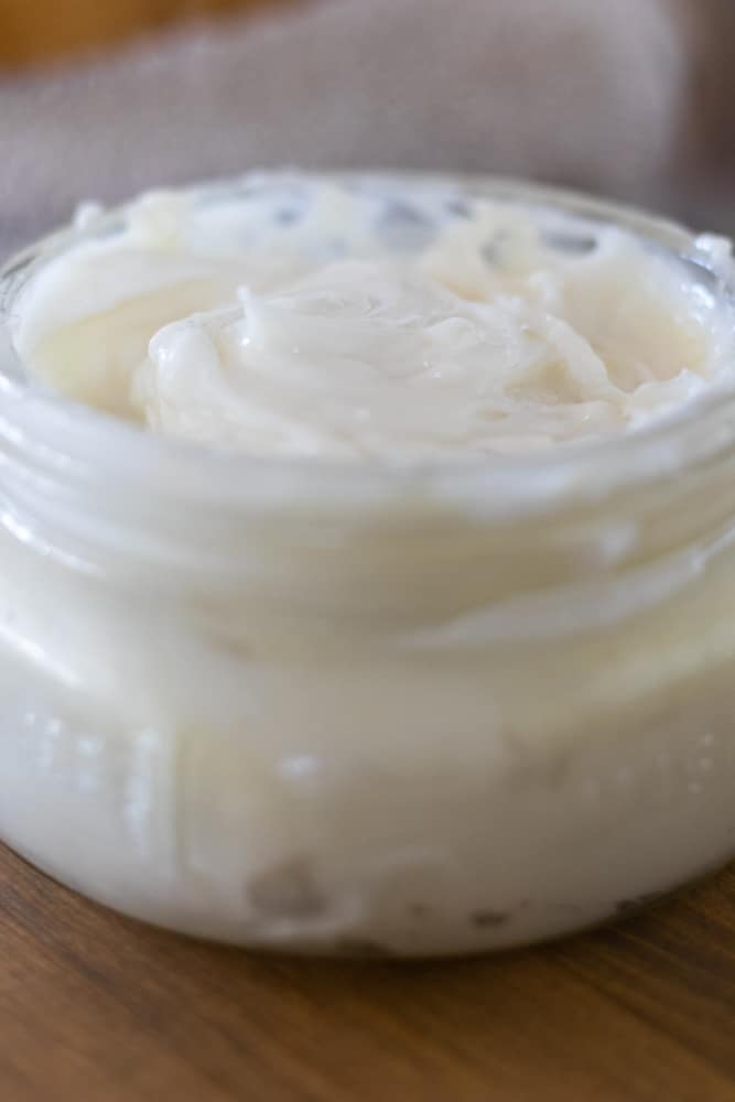 Whipped homemade shaving cream in mason jar on wood table.