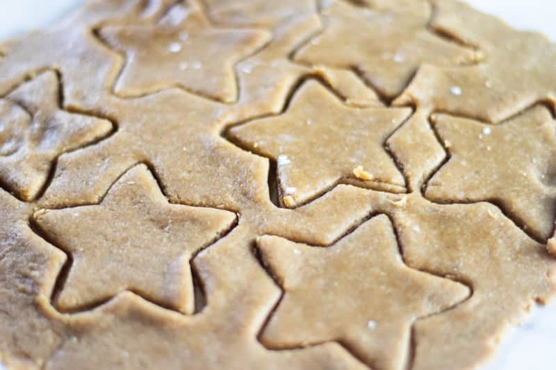 Paleo Christmas sugar cookie dough rolled out with star cookie cutter shapes.