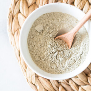 bentonite clay in white bowl with wooden spoon in it