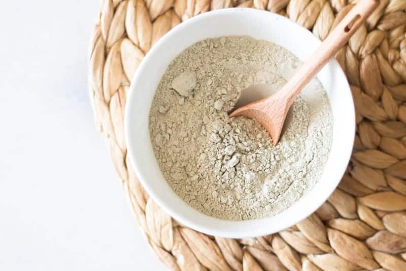 bentonite clay in white bowl with wooden spoon in it