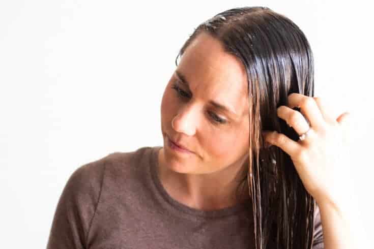 Using hands to apply a natural hair mask to wet hair.