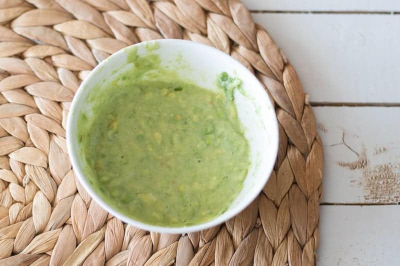 A homemade avocado hair mask in a small bowl.