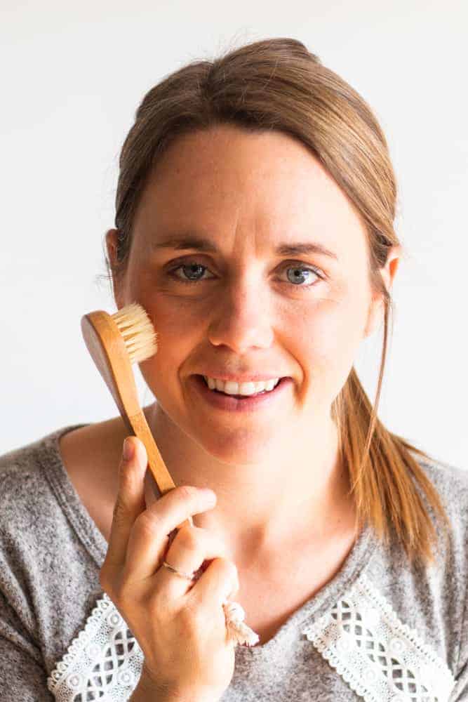 Using a soft bristle brush to dry brush the face.