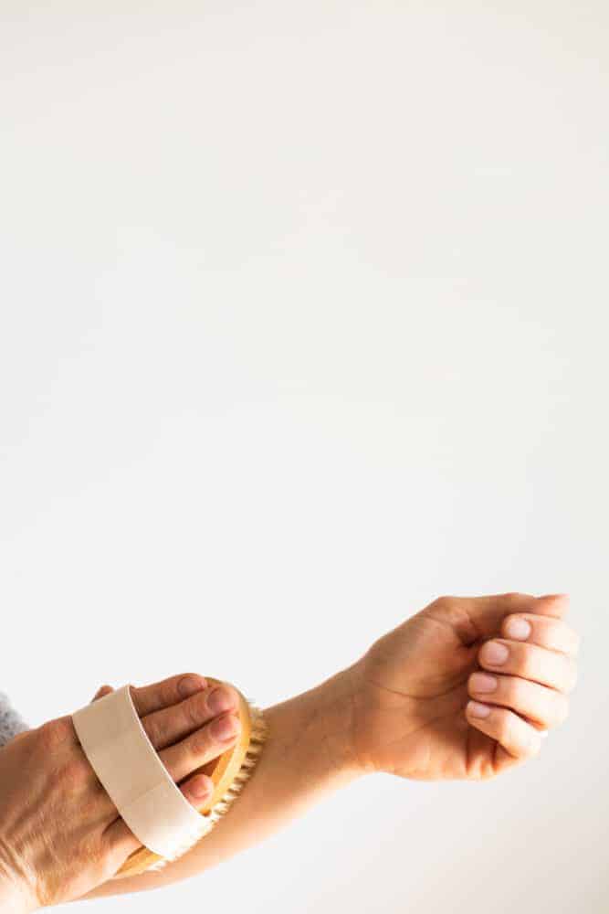 Using a dry brush to exfoliate the skin.