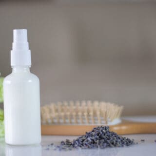 White spray bottle of leave-in conditioner with lavender buds.