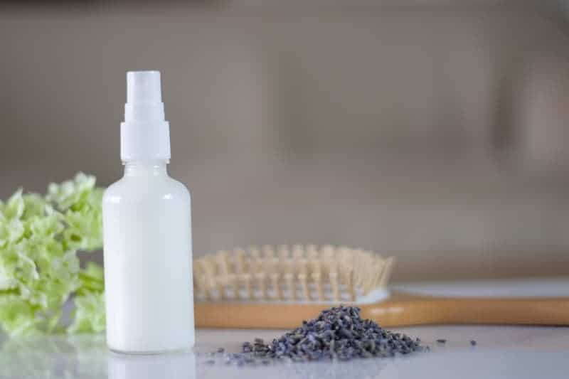 white spray bottle of leave-in conditioner with lavender buds