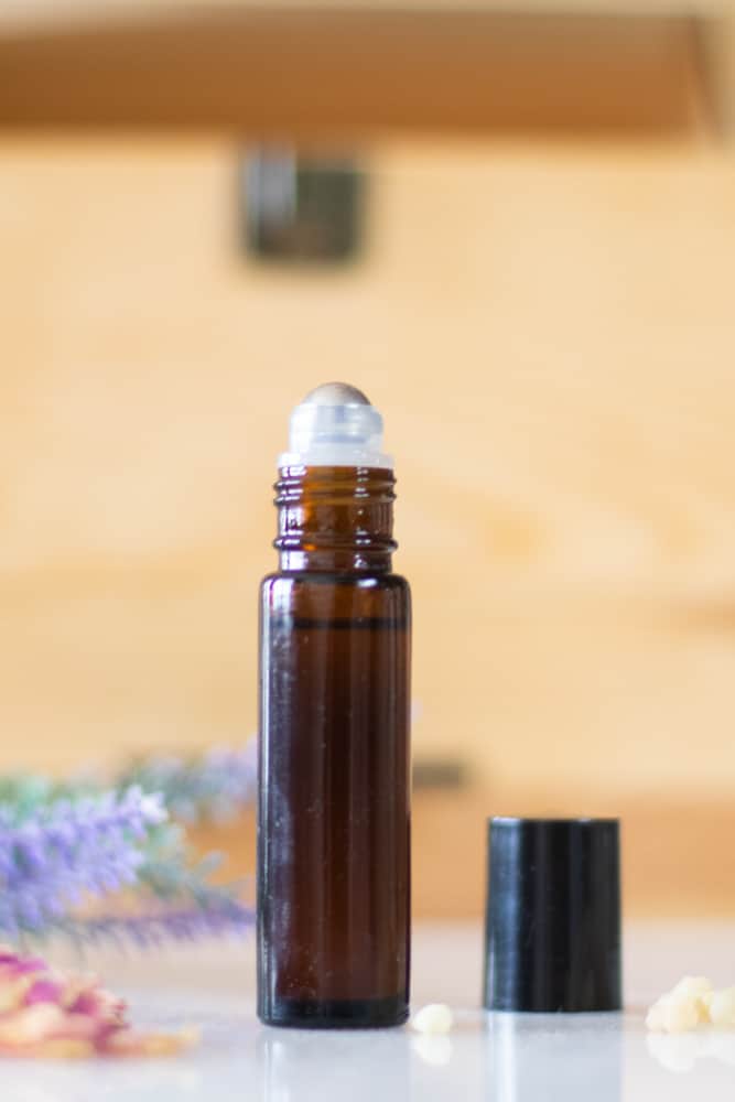 roller bottle for dark circles/bags under eyes with lavender and rose sprigs in front of wooden chest