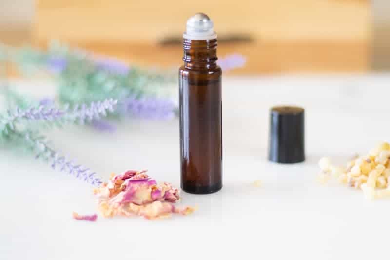 amber roller bottle with dried flowers around it on white marble top