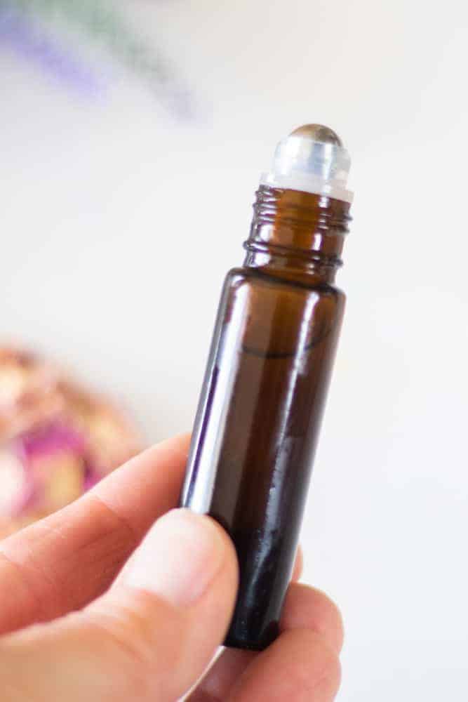 hand holding 10mL amber essential oil roller bottle for dark circles under the eyes