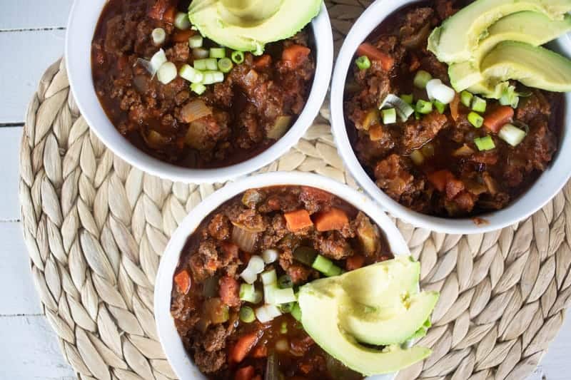 three bowls of whole30 chili topped with avocado slices and green onions