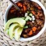 white bowl of chili with copper spoon