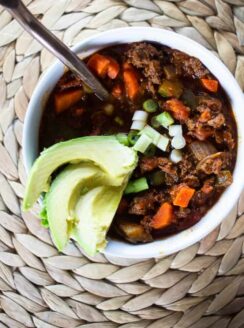 white bowl of chili with copper spoon