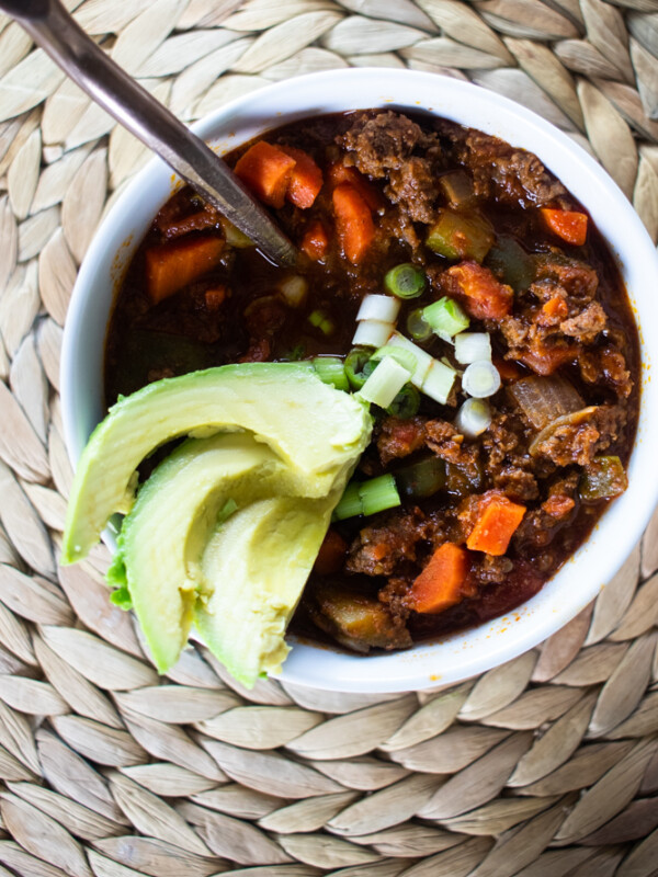 white bowl of chili with copper spoon