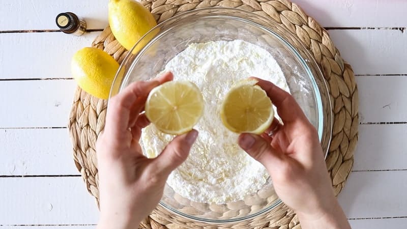 squeezing fresh lemon juice into glass bowl of dry ingredients