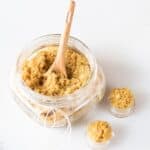 Small mason jar of lip sugar scrub with wooden spoon.
