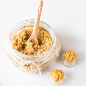 Small mason jar of lip sugar scrub with wooden spoon.