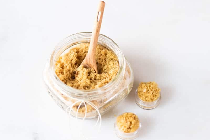 Small mason jar of homemade lip scrub with wooden spoon.